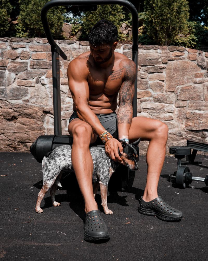 Brian Mazza wearing Black Charcoal Kane Revive shoes. Posing with his dog and sitting on an incline treadmill outdoors.
